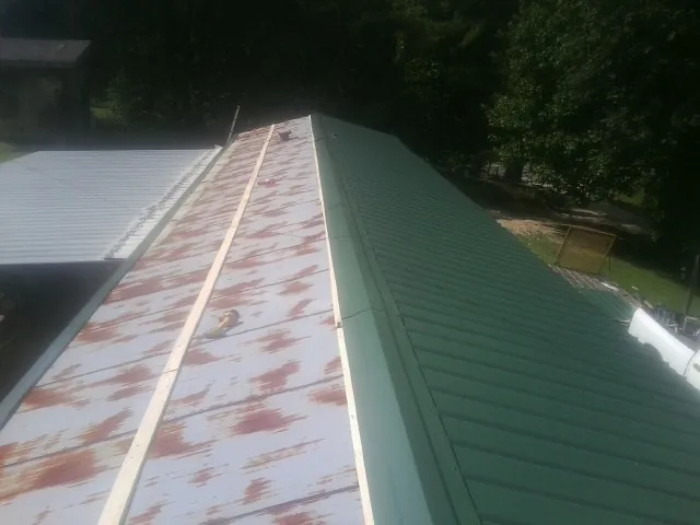 Old rusted panels beside newly installed green metal roofing — Wind Damage Roof Repair by Roofing Brothers in New Lisbon